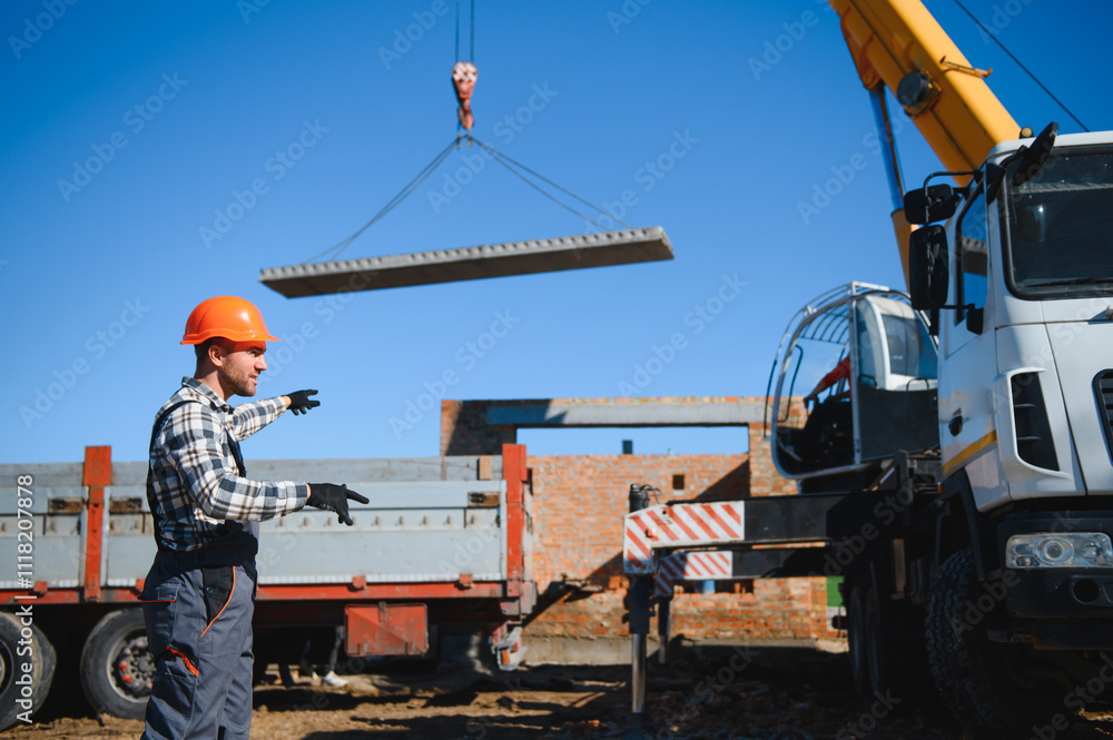 A builder controls a crane while unloading panels to cover a house A builder controls a crane while unloading panels to cover a house