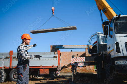 A builder controls a crane while unloading panels to cover a house