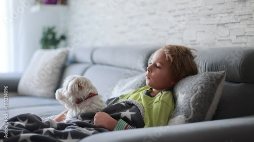 Sick child, preschool boy, lying in bed with a fever, resting at home with his pet dog, mom checking on him