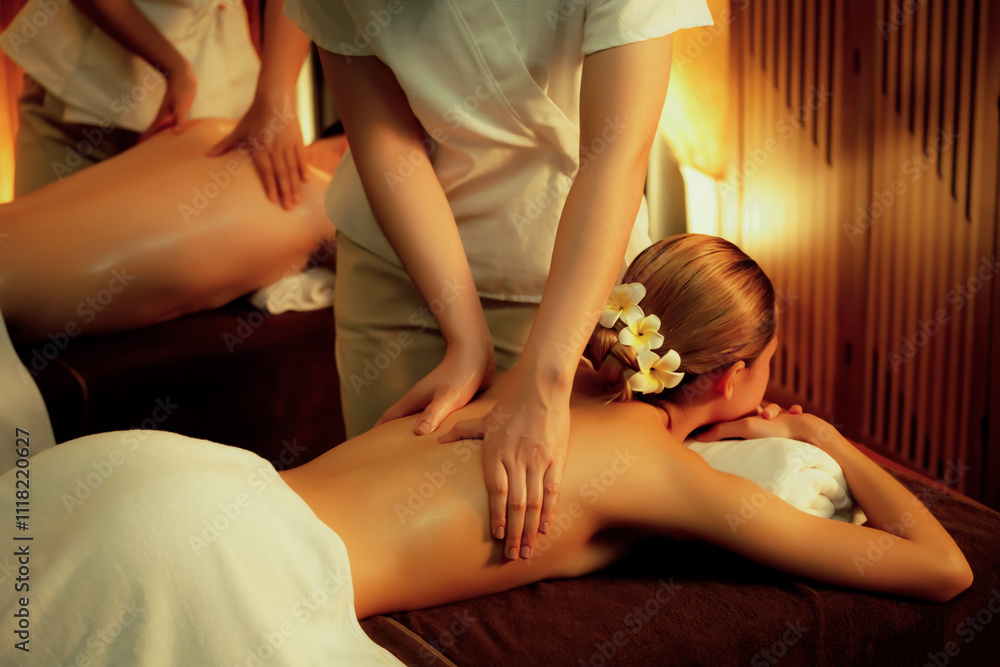 Obraz premium Caucasian couple customer enjoying relaxing anti-stress spa massage and pampering with beauty skin recreation leisure in warm candle lighting ambient salon spa at luxury resort or hotel. Quiescent