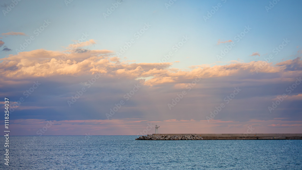 White lighthouse on breakwater, rough waves, and cloud shadows White lighthouse on breakwater, rough waves, and cloud shadows