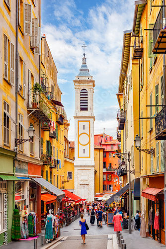 NICE, FRANCE: picturesque narrow streets of the old town, Vieux Nice, busy small shops and colorful facades of traditional houses, bell tower of Sainte Reparate church