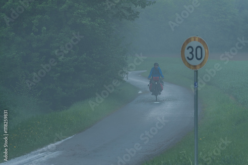 A cyclist rinding in bad weather on a lonley road in Germany in fog
