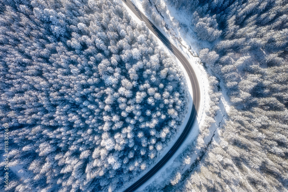 Natural winter landscape from air. Aerial view on the road and forest at the winter time. Winter chill. Forest and snow. Photo for background, wallpaper, postcards.