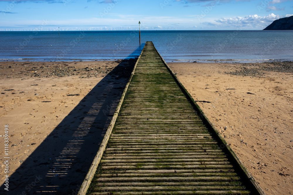 Obraz premium Wooden jetty leading out to sea on beach
