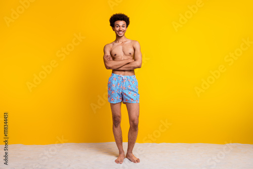 Fototapete Young man smiling confidently in stylish swimwear against vibrant yellow backgro