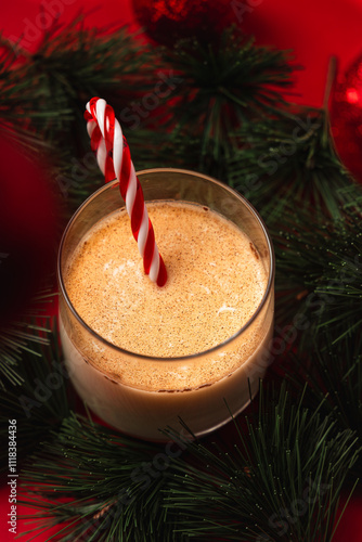 Macro vertical view of eggnog with pine needles on a red background