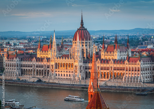 Photography The photo captures the Hungarian Parliament Building in Budapest during sunset, beautifully reflecting the warm sunlight on its Neo-Gothic architecture along the Danube River