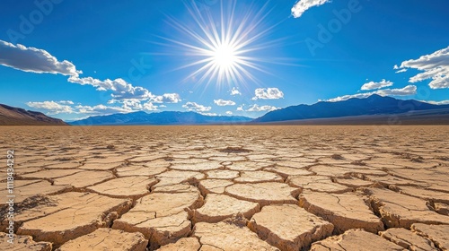 Bright Sun Over Cracked Desert Landscape With Mountains photo