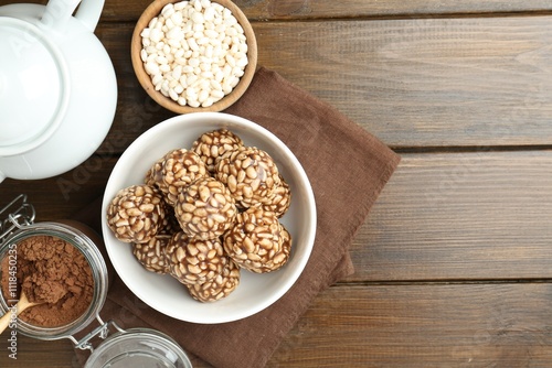 Tasty chocolate puffed rice balls, ingredients and teapot on wooden table, flat lay. Space for text photo