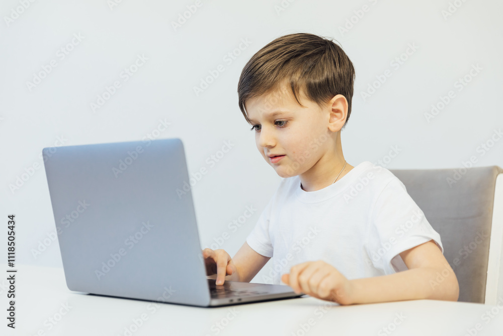 Little boy learning to play on laptop online at table Little boy learning to play on laptop online at table