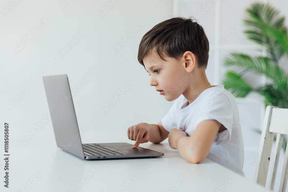 Little boy learning to play on laptop online at table Little boy learning to play on laptop online at table