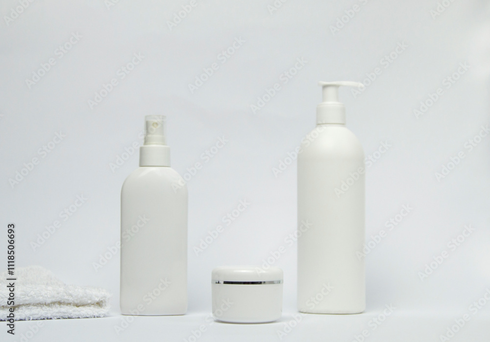 Set of white cosmetic bottles mockup with a towel on white background. Set of white cosmetic bottles mockup with a towel on white background.
