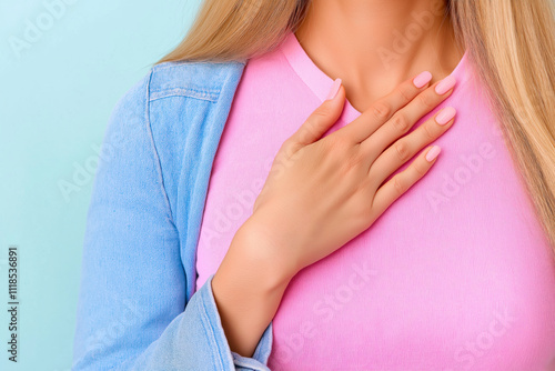 Wallpaper Mural Woman touching her chest in a casual setting, wearing a pink top with a jacket against a light backdrop. a problem with breathing or lungs, a cold. Torontodigital.ca