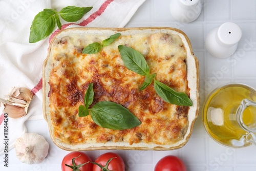 Delicious cooked lasagna with basil served on white tiled table, flat lay