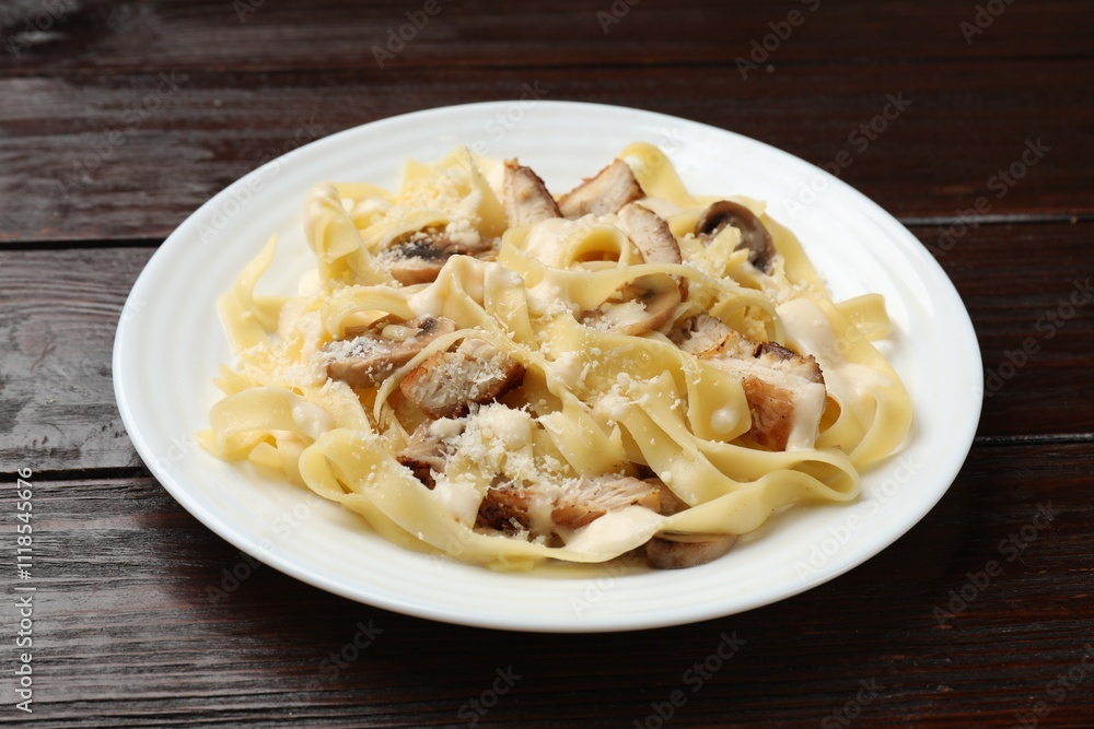 Tasty Alfredo pasta with chicken and mushrooms on wooden table, closeup