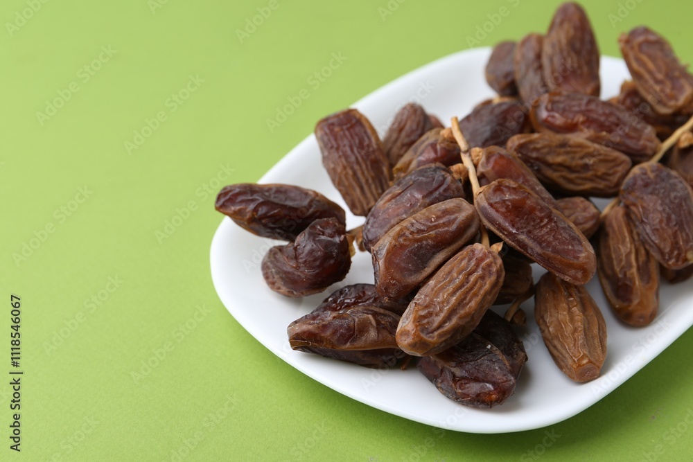Tasty dried dates on green background, closeup. Space for text Tasty dried dates on green background, closeup. Space for text
