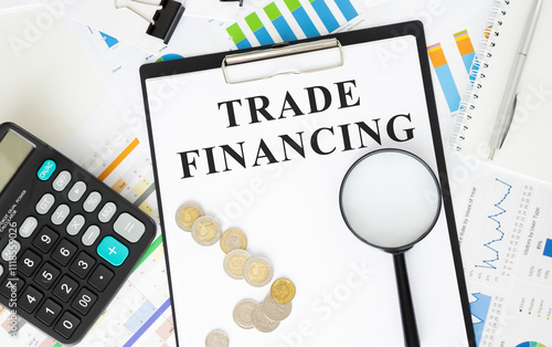 Business and finance concept. On the table there is a clock, a pen, a calculator and a business card on which the text is written - TRADE FINANCING photo