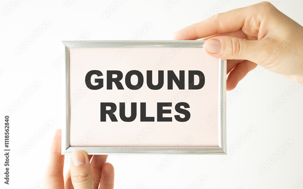 Closeup on businessman holding a card with text GROUND RULES, business concept image with soft focus background and vintage tone Closeup on businessman holding a card with text GROUND RULES, business concept image with soft focus background and vintage tone