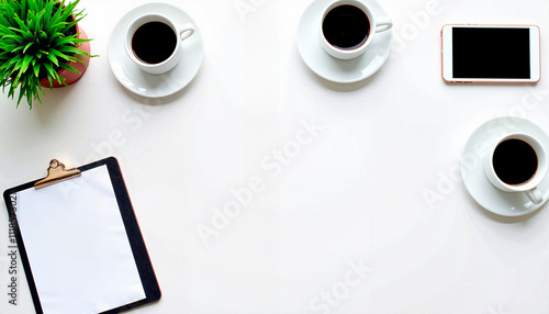 Office table setup with coffee cups, clipboard, and phone