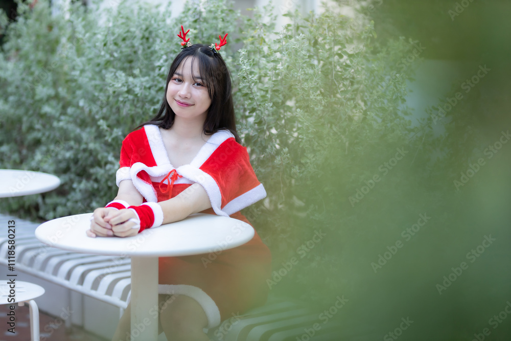 Portrait Cute Smiling asian girl in red santa with looking to the camera near Christmas greeting picture parcel decoration on Christmas tree background Decoration During Christmas and New Year.