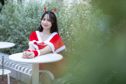 Obraz na płótnie Portrait Cute Smiling asian girl in red santa with looking to the camera near Christmas greeting picture parcel decoration on Christmas tree background Decoration During Christmas and New Year. w salonie