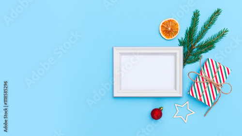 Christmas frame ornament with gift box, eve fir, drie orange and toys on light blue background. Minimal New Year holiday concept, flat lay, top view, place for text photo