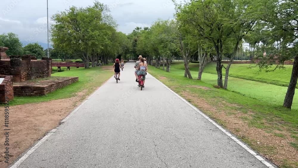 Smiling tourist family cycling joyfully through the Sukhothai Historical Park in Thailand
