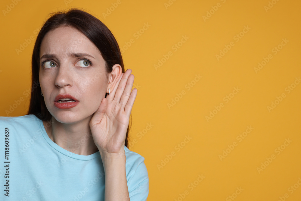 Woman showing hand to ear gesture on orange background, space for text Woman showing hand to ear gesture on orange background, space for text
