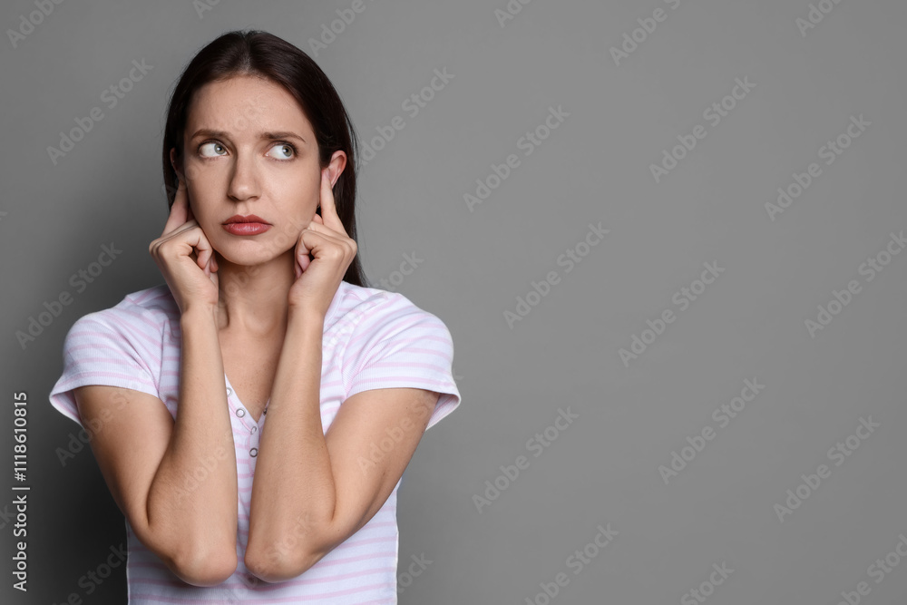 Woman covering her ears with fingers on grey background, space for text Woman covering her ears with fingers on grey background, space for text