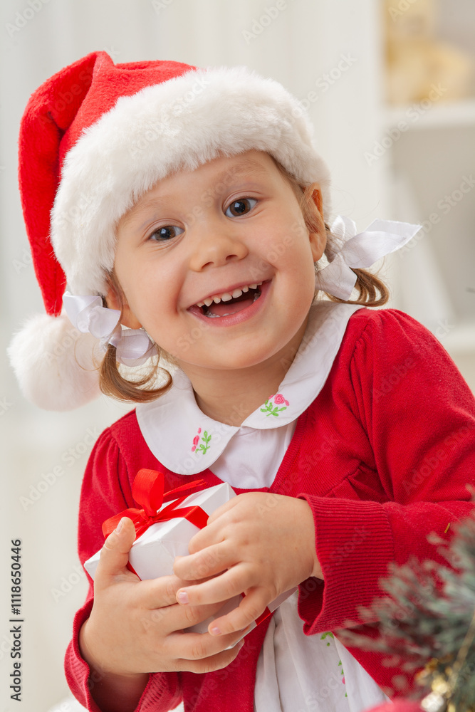 Portrait of little cute girl in Santa Claus costume with Christmas present