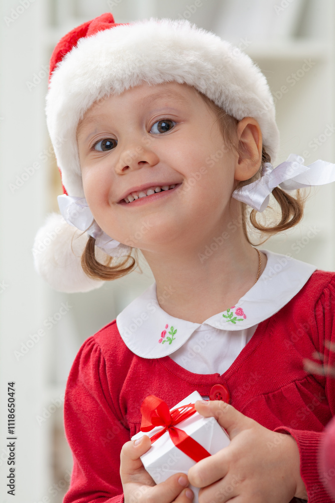 Portrait of little cute girl in Santa Claus costume with Christmas present
