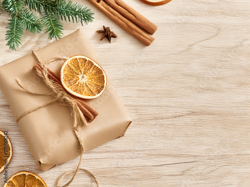 Geschenk mit naturpapier eingepackt, darauf ein paar getrocknete Orangen und daneben ein paar Zimtstangen photo