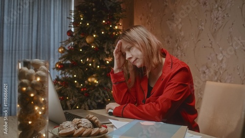 Sad worried woman with cash money and Christmas tree on background, mortgage payment problem.