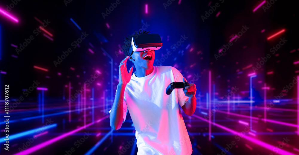 Fototapeta premium Teenager holding joystick and wearing VR goggles while enjoy playing games at neon abstract background. African man enjoy controlling controller and using augmented reality technology. Ingenuity.