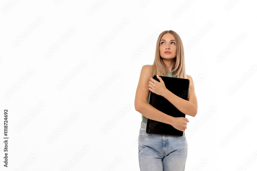 Young woman holding a laptop while looking thoughtfully into the distance in a bright indoor setting Young woman holding a laptop while looking thoughtfully into the distance in a bright indoor setting