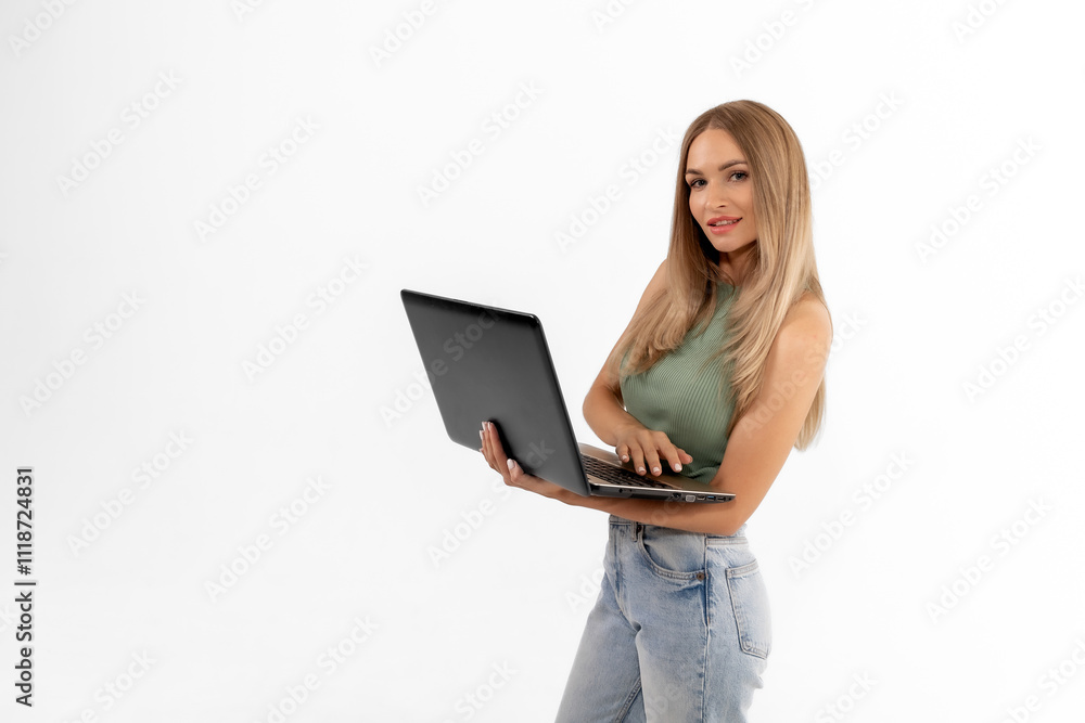 Young woman working on a laptop while posing against a white background in a bright, minimalist studio environment Young woman working on a laptop while posing against a white background in a bright, minimalist studio environment