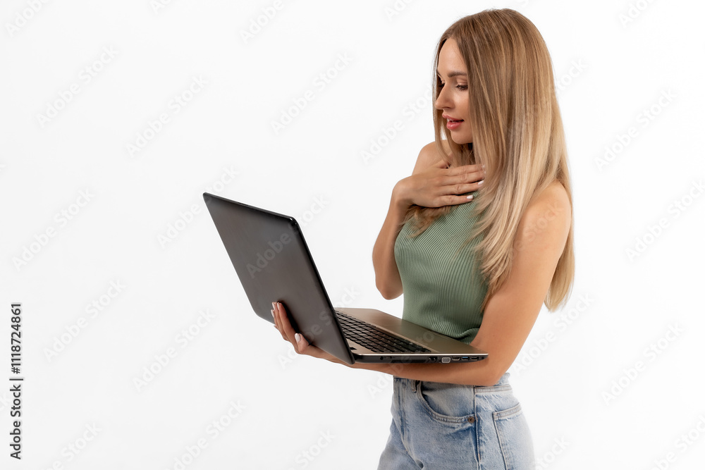 Fototapeta premium Young woman expresses surprise while using a laptop with a white background, showcasing her engagement with technology and digital communication