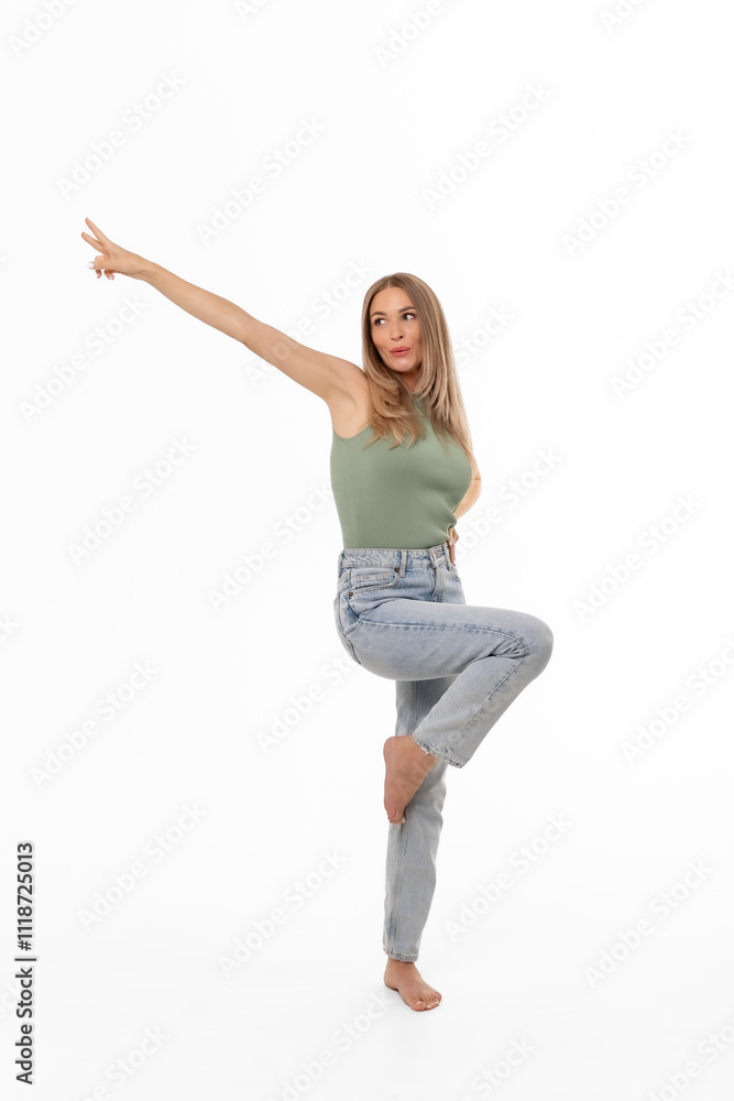 A young woman strikes a dynamic pose while balancing on one leg against a plain white background in a bright indoor setting A young woman strikes a dynamic pose while balancing on one leg against a plain white background in a bright indoor setting