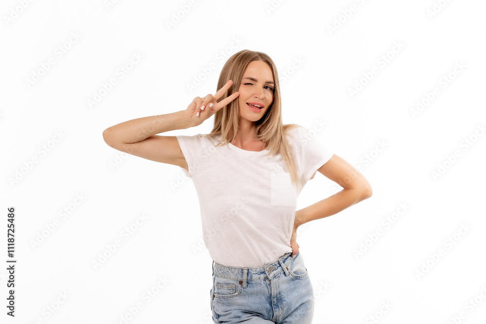 A smiling woman poses playfully with a peace sign against a bright white background, showcasing casual fashion and joyful expression A smiling woman poses playfully with a peace sign against a bright white background, showcasing casual fashion and joyful expression