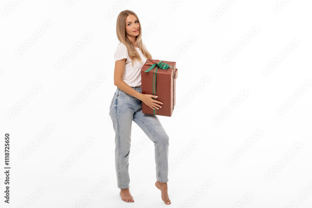 A woman holding a large gift box while standing barefoot against a white background, showcasing a festive spirit ideal for holidays A woman holding a large gift box while standing barefoot against a white background, showcasing a festive spirit ideal for holidays