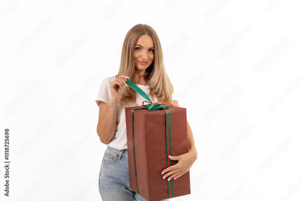 A woman smiling while holding a large brown gift box wrapped with a green ribbon against a white background A woman smiling while holding a large brown gift box wrapped with a green ribbon against a white background