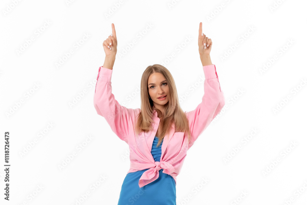 A woman in a pink blouse and blue dress poses cheerfully with her hands raised against a white background A woman in a pink blouse and blue dress poses cheerfully with her hands raised against a white background
