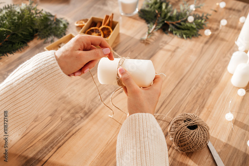 Close-up of a young woman's hands decorating candles for Christmas or New Year. Decorating items for the holiday and making gifts.