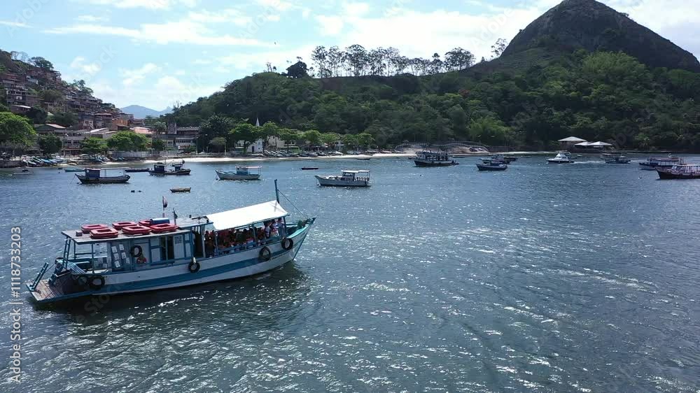 Aerial view of a blue and white tourist boat sails through the calm waters of Guanabara Bay, with the beautiful scenery of Rio de Janeiro and Niterói in the background. Aerial view of a blue and white tourist boat sails through the calm waters of Guanabara Bay, with the beautiful scenery of Rio de Janeiro and Niterói in the background.
