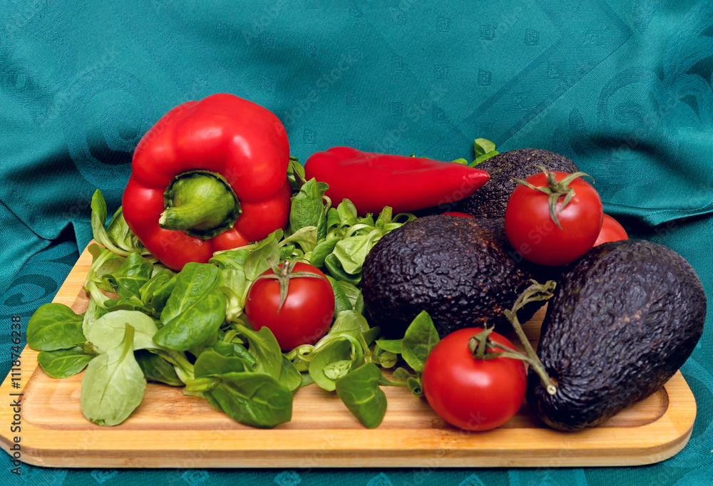 Ripe Avocado on a Wooden Board with Fresh Spinach, Red Tomatoes, and Red Peppers Ripe Avocado on a Wooden Board with Fresh Spinach, Red Tomatoes, and Red Peppers
