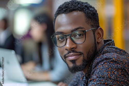 An unidentified young Black man is engaged in remote learning, watching a video on his laptop and jotting down notes from the female teacher's explanations displayed on a blackboard.