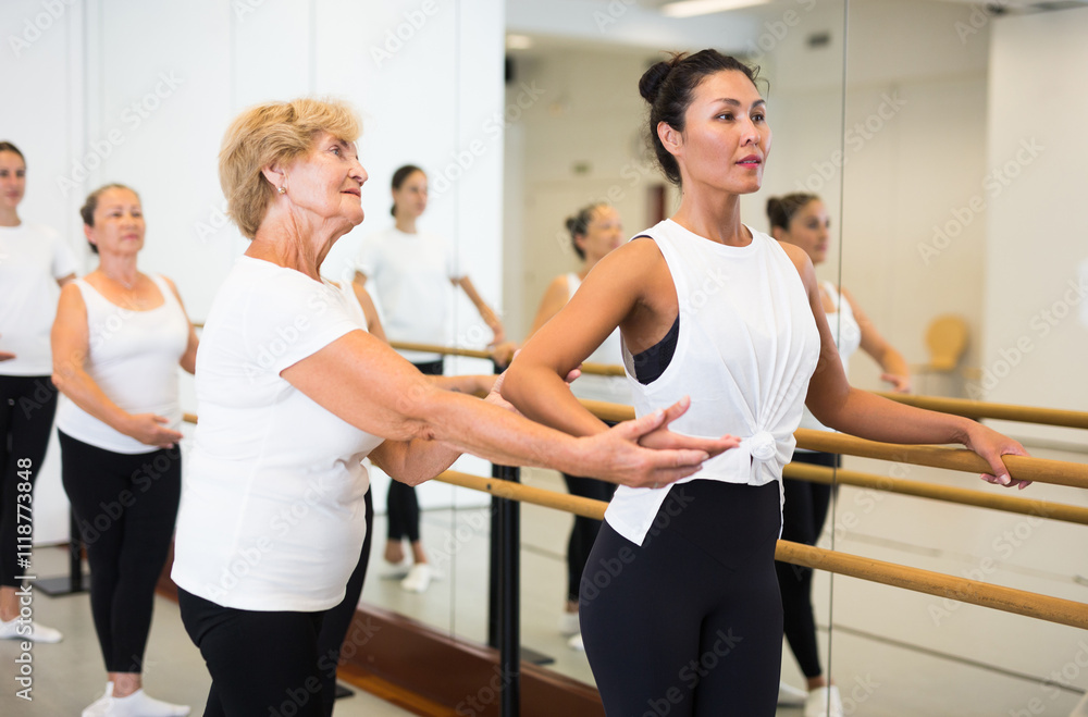 Dancing Asian woman doing ballet in a female group in the studio is standing in a ballet stance, where the choreographer ..helps to perform the exercise correctly