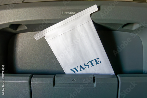 motion sickness bag in an airplane seat back labelled Waste