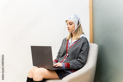 A pretty girl is sitting in a psychology office while interacting with a laptop and undergoing transcranial direct current stimulation. TDCS concept.